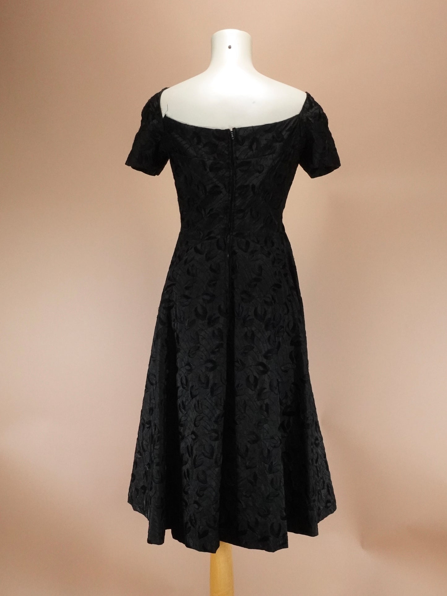 Black lace dress on a mannequin against a beige background