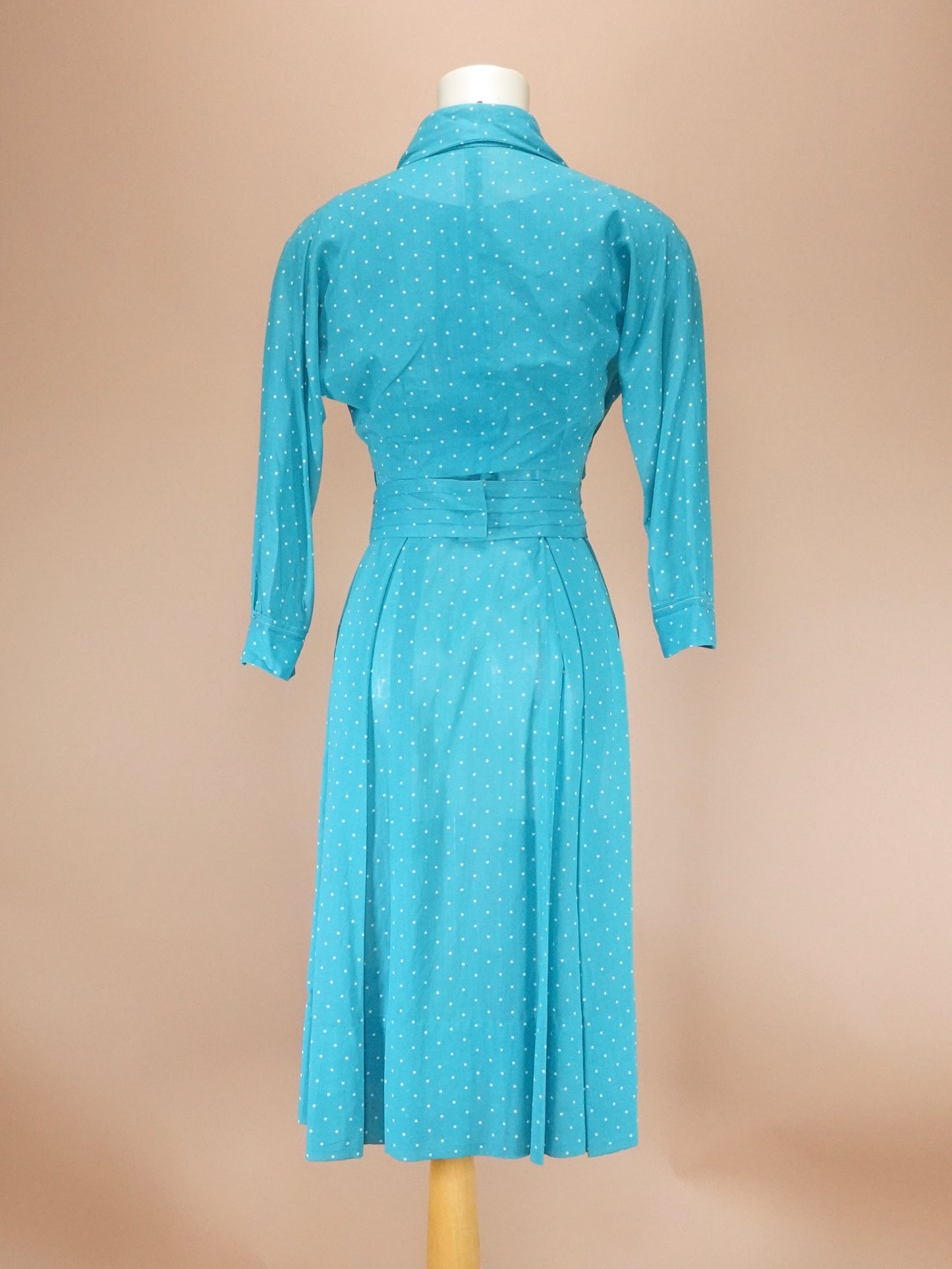 Teal dress on a mannequin against a beige background