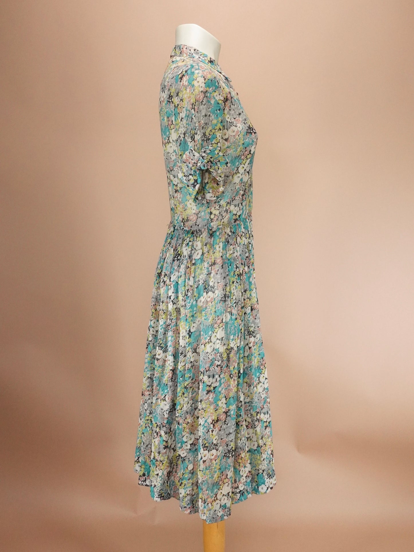 Floral dress on a mannequin against a beige background