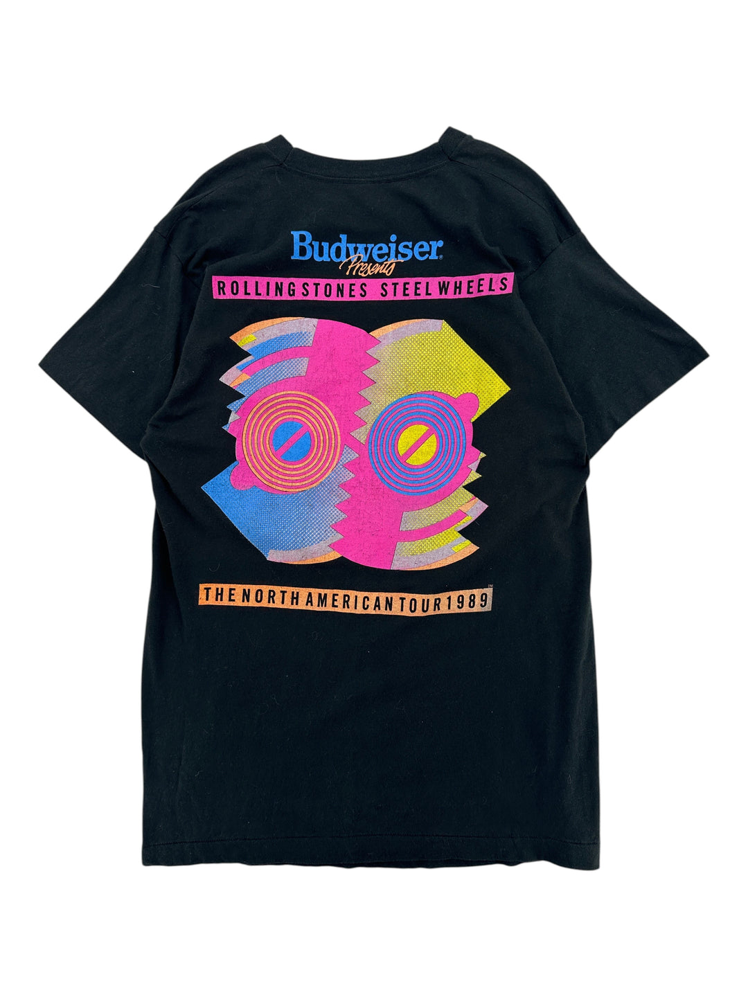 A black short-sleeve t-shirt shown flat against a white background, featuring a colorful graphic print of the Budweiser x Rolling Stones Steel Wheels collaboration from their 1999 North American Tour.
