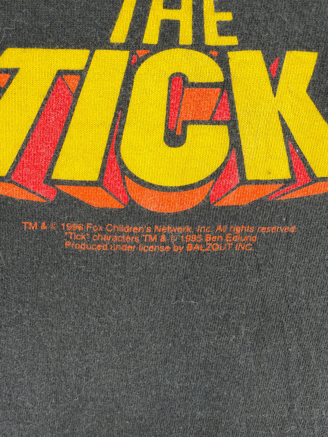 Exile Vintage 1990s The Tick graphic t-shirt featuring yellow and orange logo print on black cotton fabric