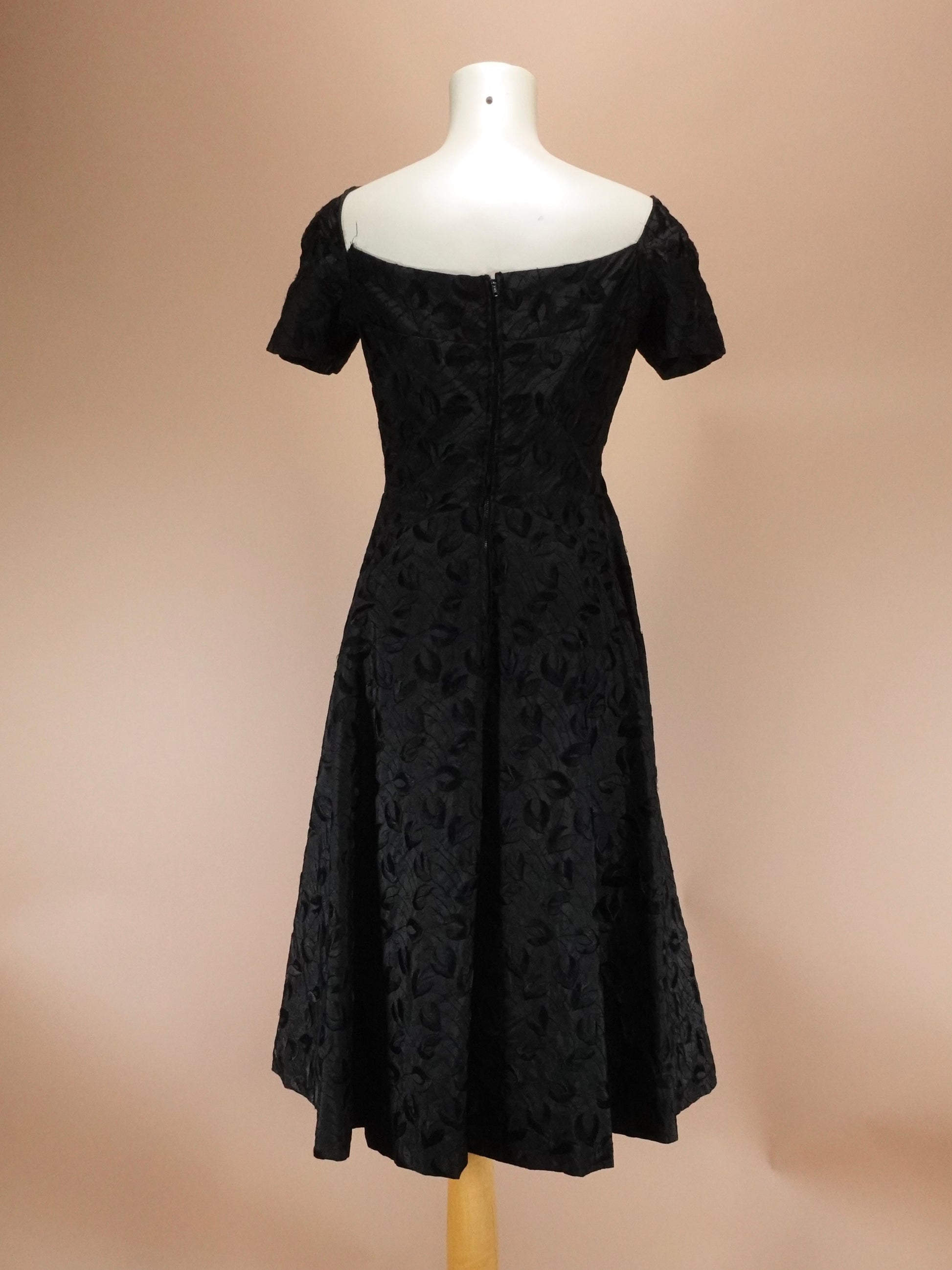 Black lace dress on a mannequin against a beige background